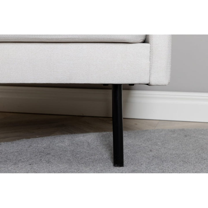 Närbild på Zoom ljusbeige fåtöljs svarta metallben och undre sitskant